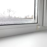Vandens lašeliai ant vidinės plastikinio lango stiklo pusės