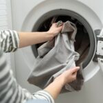 Moteris iš skalbyklės išima išskalbtas užuolaidas