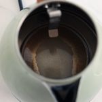 Iš viršaus matomas atidarytas elektrinis virdulys su kalkių apnašomis dugne.